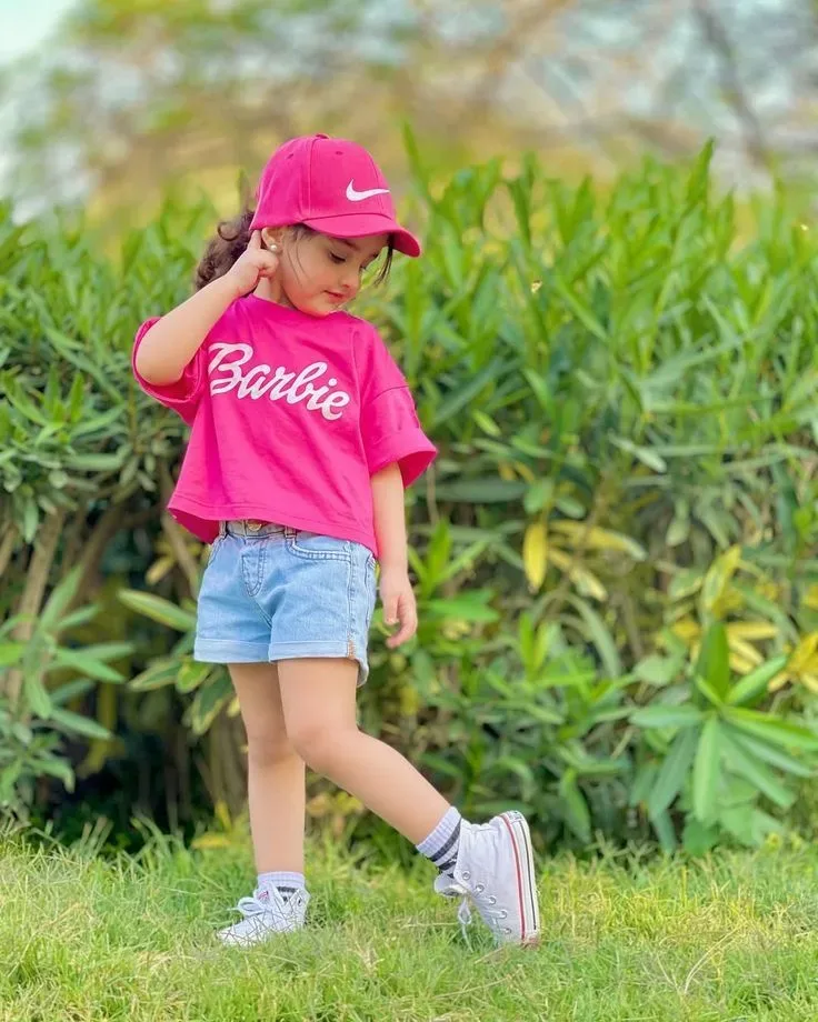Adorable Little Girl Portrait In Pink Barbie T-shirt & Cap On Lawn AI Photo Prompt preview example result
